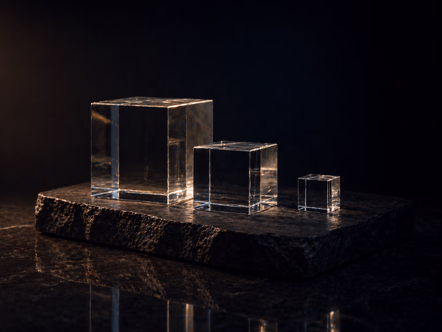 Three transparent glass cubes on dark slate — clarity, restraint, transparency